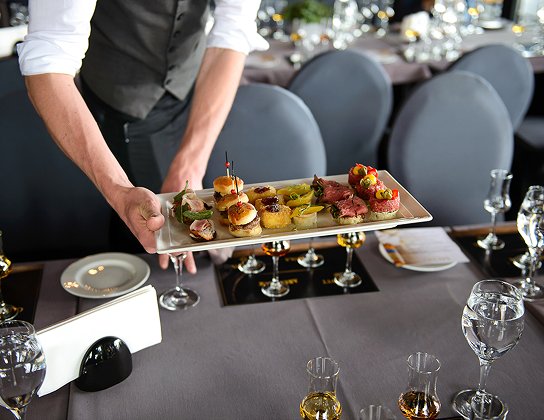 A server presenting a tasting plate of canapes at a members' supper